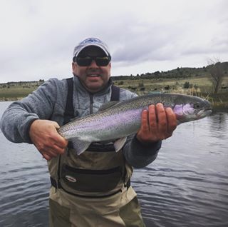 A client with a large rainbow trout from a private lake.